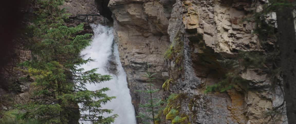 A waterfall rushes down the side of a canyon