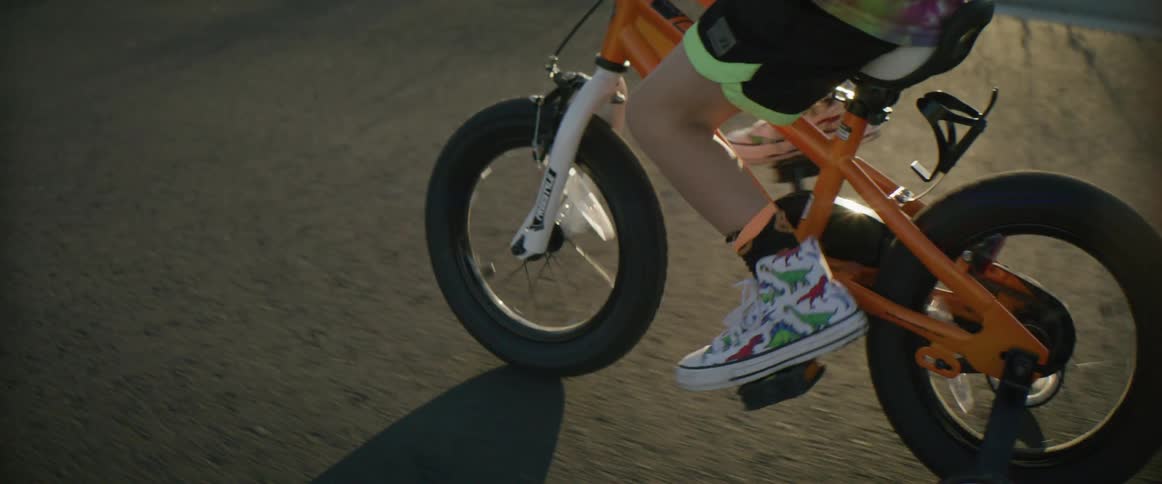 Young boy riding a bicycle with training wheels on the street at morning