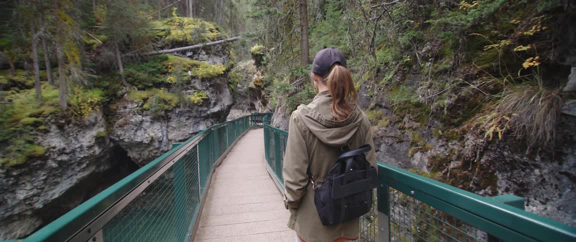 A woman hiking on a trail with a bridge