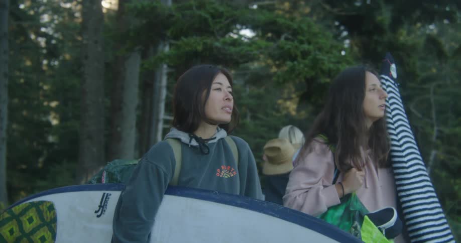 A group of female surfers tries to find spot to surf next to forest