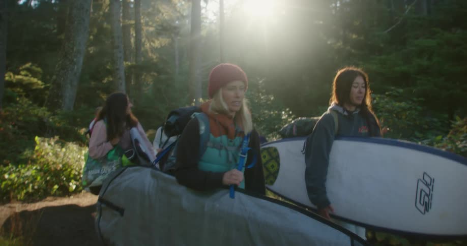 Group of woman walking through the forest carrying surfboards