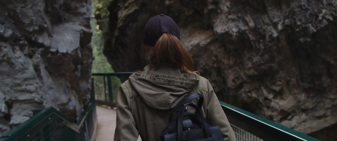 Young woman walking on a bridge inside a canyon close to the forest