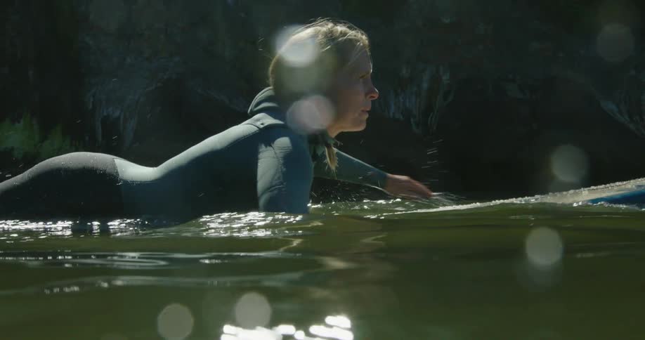 Closeup of female surfer paddling on surfboard in the ocean