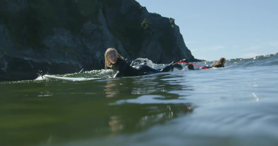 A woman paddles hard trying to catch a wave to surf