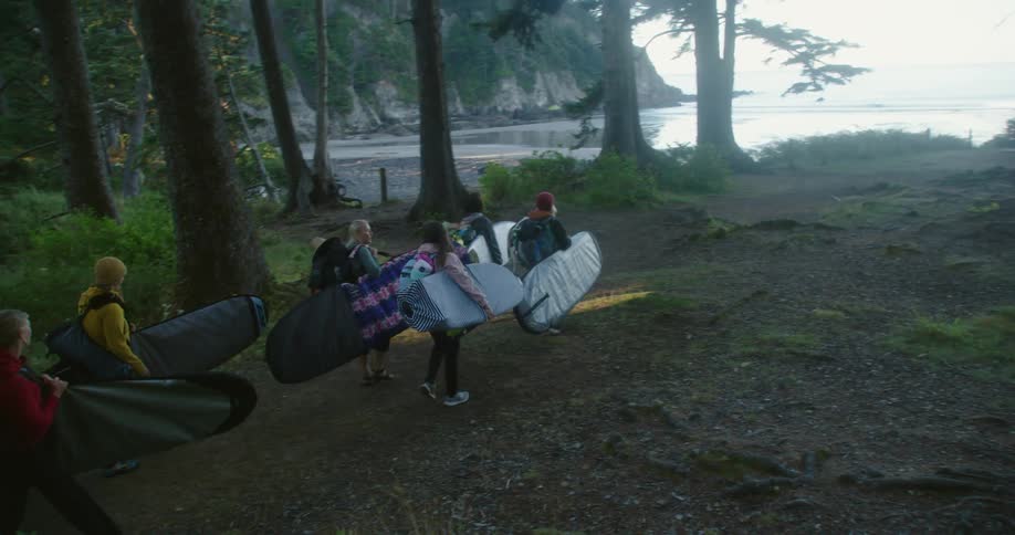 A group of women carry bags towards the ocean