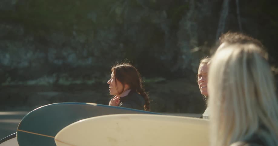 A group of female surfer carrying surfboards goes surfing