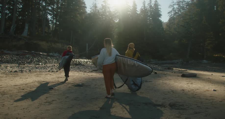 A group of women carry surfboards to a small creek