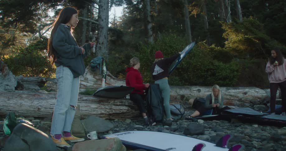 A group of people unpacking surfboards on the beach