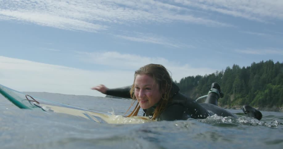 Close up of female surfer paddling on surfboard in the ocean