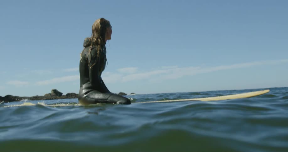 A woman is sitting on a surfboard in the ocean water