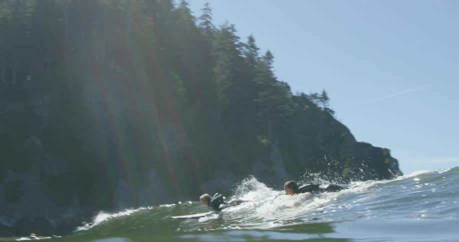 A group of people ride a wave on surfboards