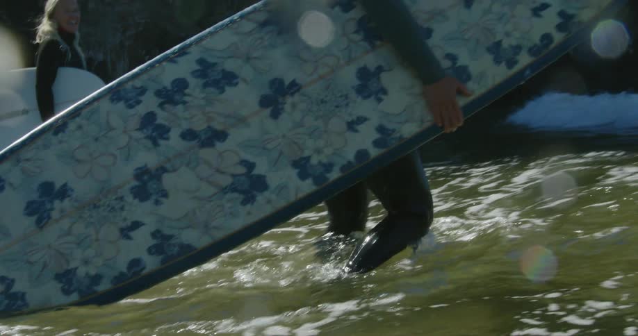 Two friends are walking on the beach with surfboards