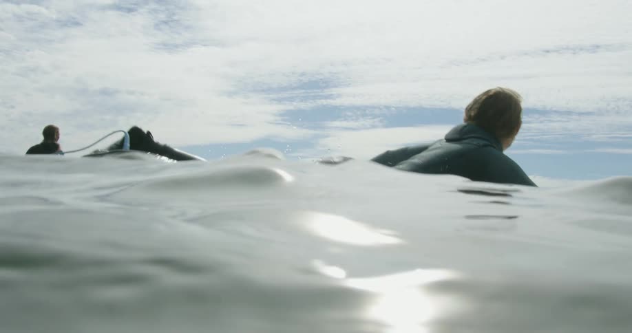 Woman swimming over a surfboard in the ocean close to the mountains in the coast