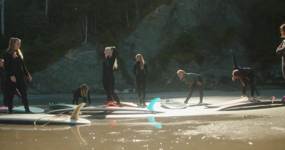 A group of women are at the beach with their surfboards