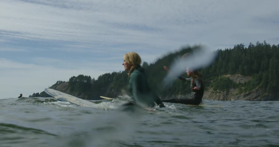 Two women on surfboards out in the ocean