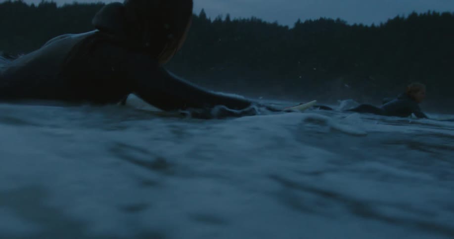 Women paddle on their surfboards in the rough water