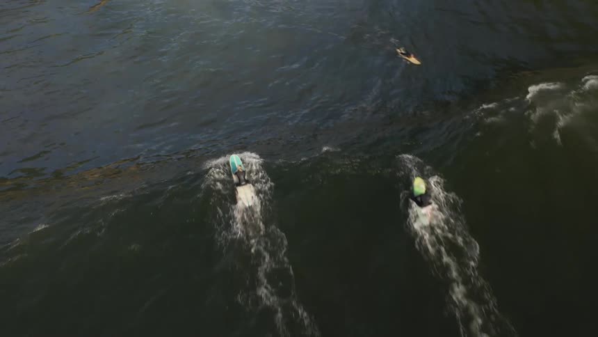 A large wave knocks over a group of surfers
