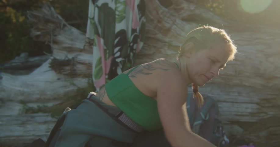 A woman is cleaning her surfboard at dusk