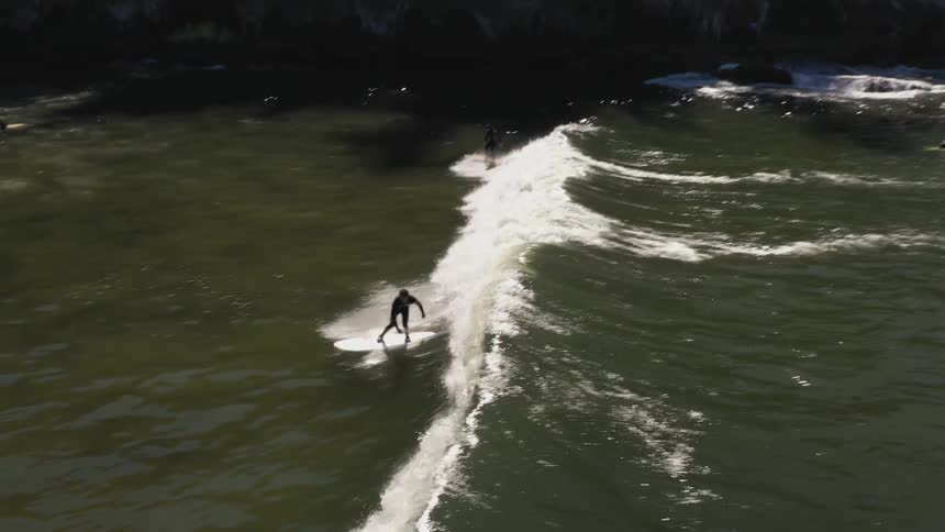 Aerial view of women surfing on the waves close to the beach in the coast near the mountains