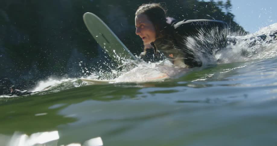 Three women paddle on surfboards in the ocean