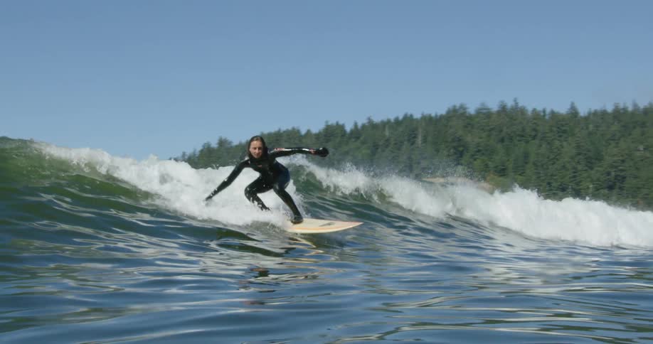A woman is surfing a wave on a sunny day