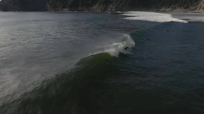 People are surfing in the water as waves roll in along the coast