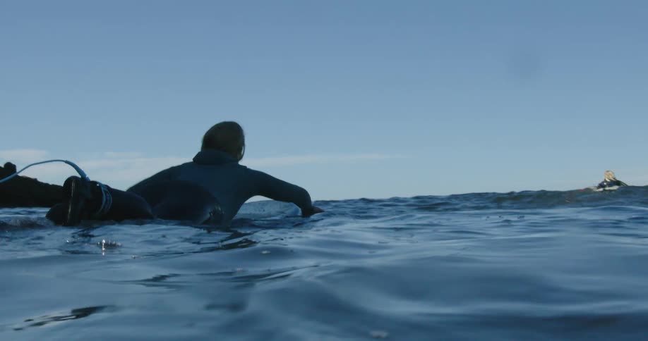 A woman is surfing on ocean water at midday