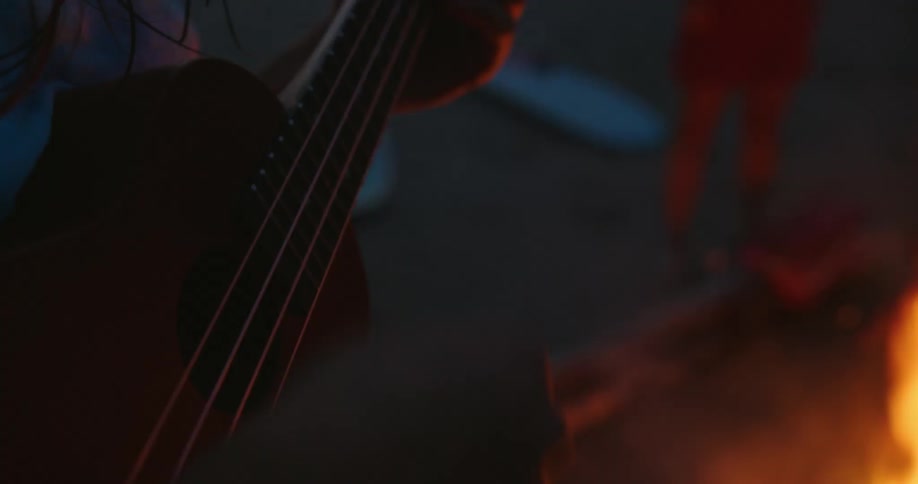 A person is playing guitar by the campfire