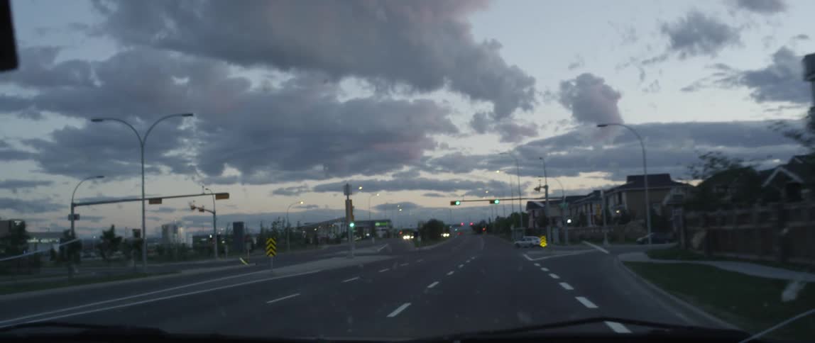 A car is driving down a road at sunset