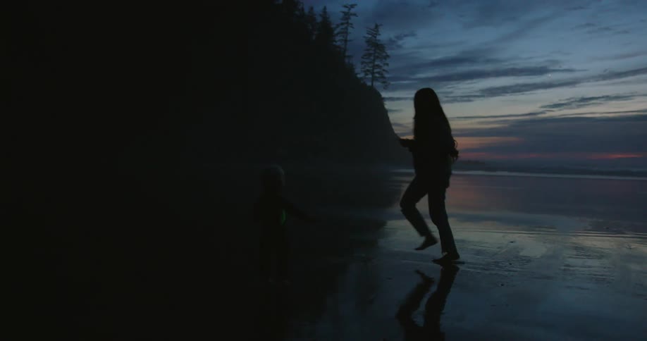 A woman runs around the beach with a child