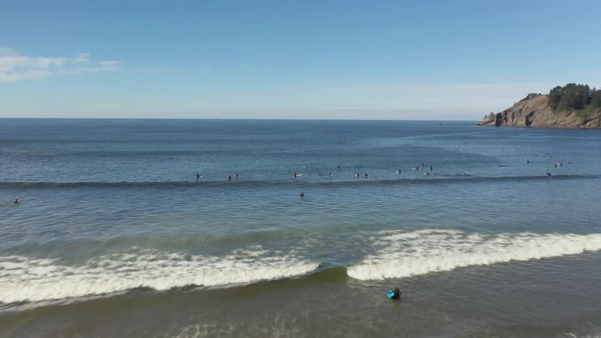 Surfers travel from the beach out into the ocean