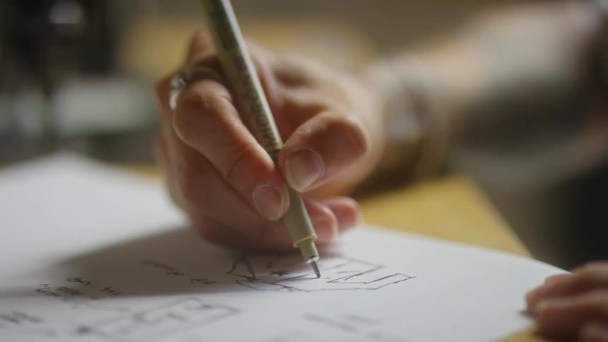 A person is holding a pen in their right hand and drawing a picture