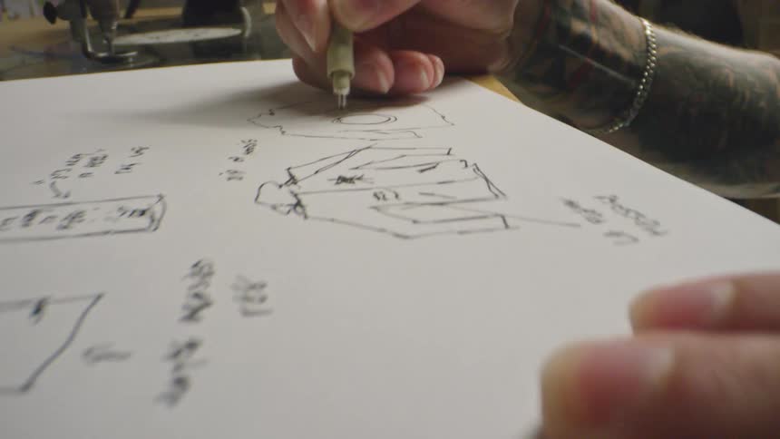 A man is drawing on a paper with a mechanical pencil