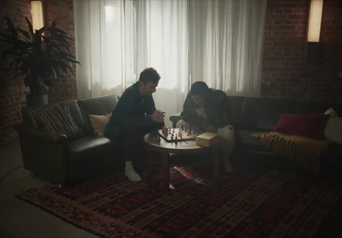 Two friends have fun playing chess over a coffee table in the living room at home
