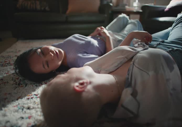 Young couple talk to each other laying on the floor of the living room