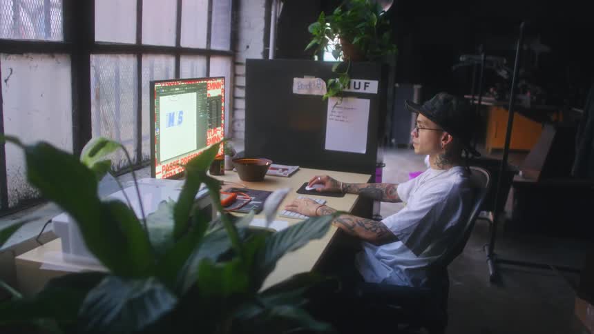 Man sitting at computer manipulates large letters showing on monitor