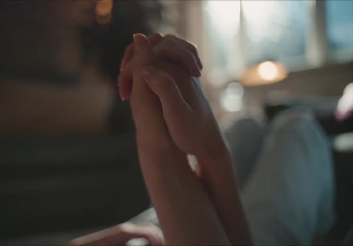 A couple hold hands as they together on the couch