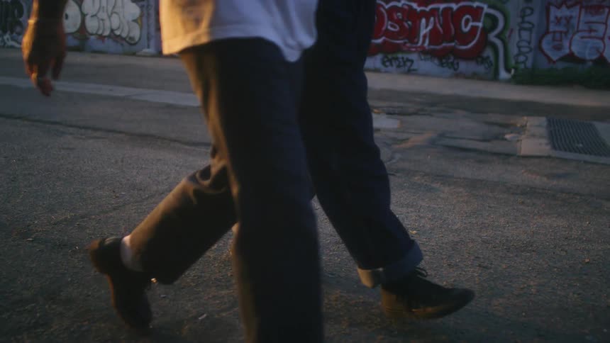 Two men walk past a building covered in grafitti