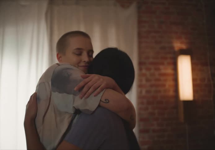 Two women hug and dance closely together in a home