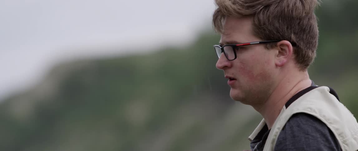 Man outside wearing glasses staring off