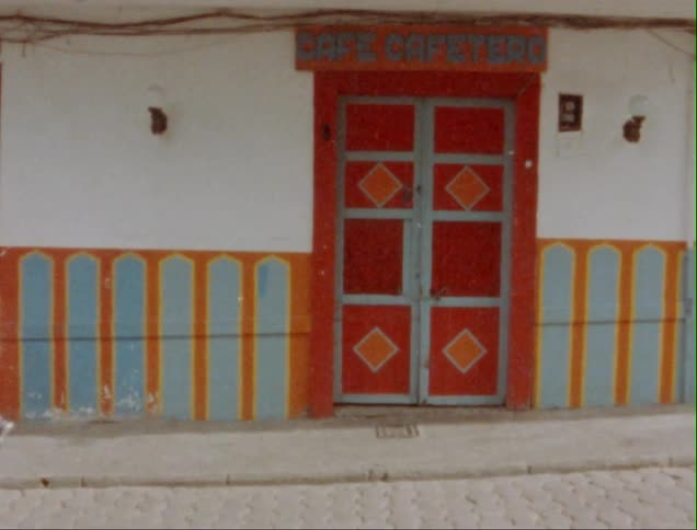 Female pedestrian walks past colorful entrance to a cafe