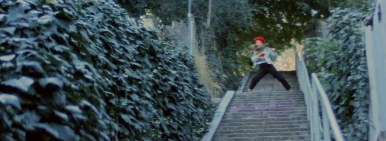 Blonde woman wearing denim jacket and red hat dancing on the stairs outdoor at morning