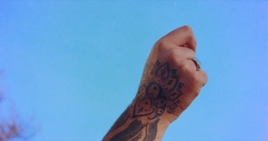 Person with tattooed arm and hand snaps finger in the air