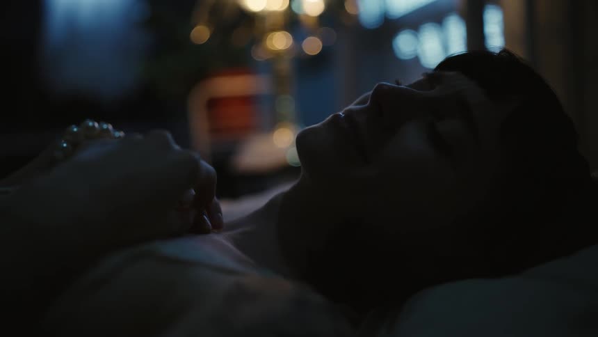 Silhouette of a woman laying in bed at home near a window at night