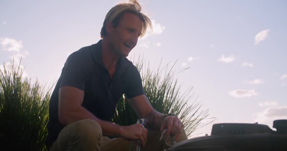 Man drinks water while resting after mowing the lawn at morning