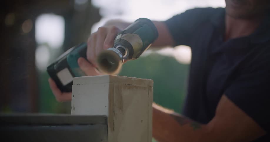 A man is using a tool to sand a box