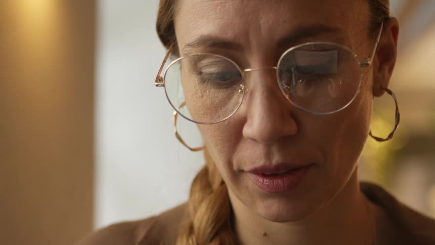 A portrait of a typing woman with big glasses