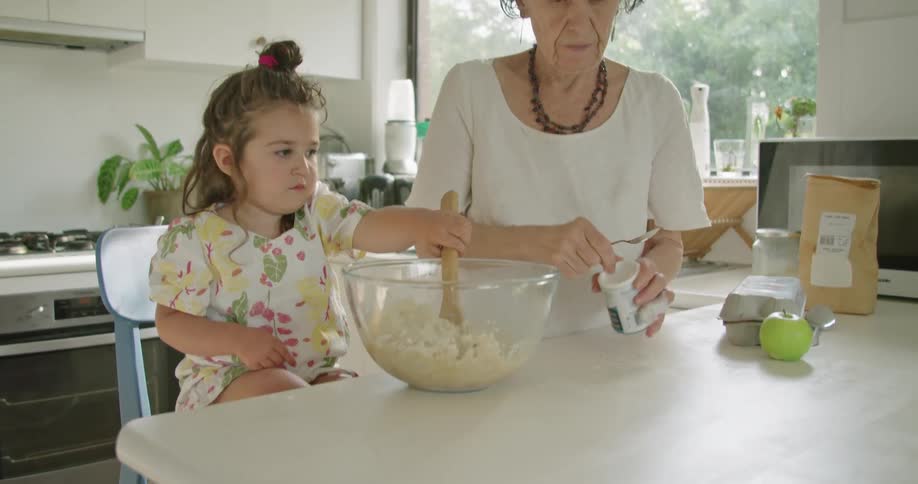Grandmother and granddaughter cooking in the kitchen at home