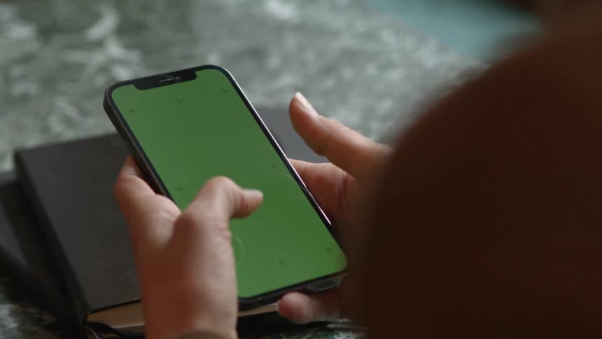 Woman types and starts a call on a smartphone with a replaceable green screen