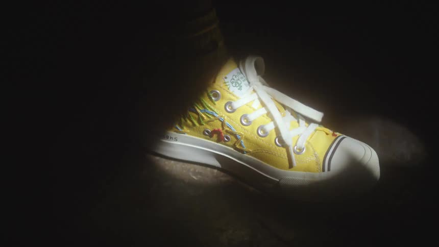 A yellow shoe on a persons foot as they turn around and tap their foot